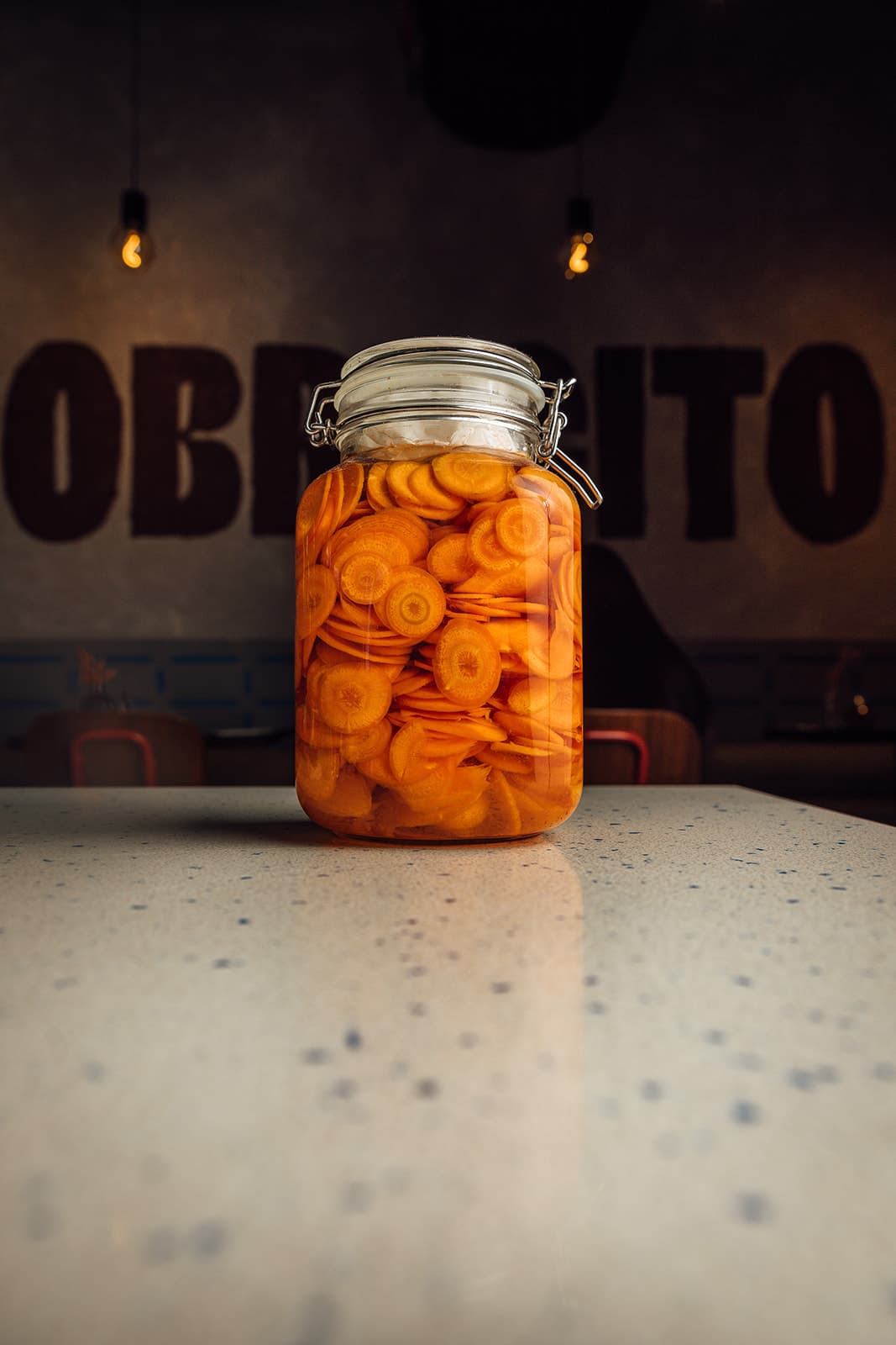 A jar of pickled carrots in front of the Pobrecito sign